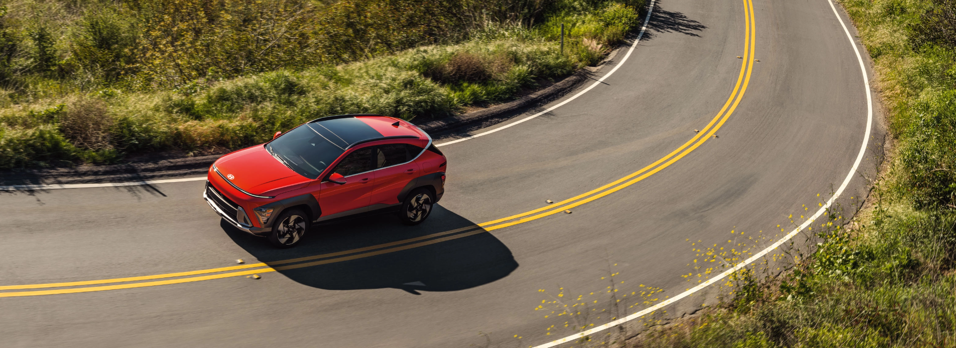 Close-up view of the side of a red Hyundai SUV with black alloy wheels, set against a scenic background.