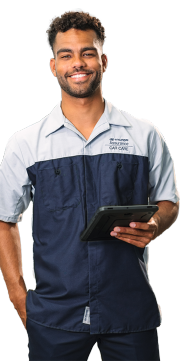 Smiling Hyundai technician in uniform, with arms crossed, standing confidently and holding a tablet.